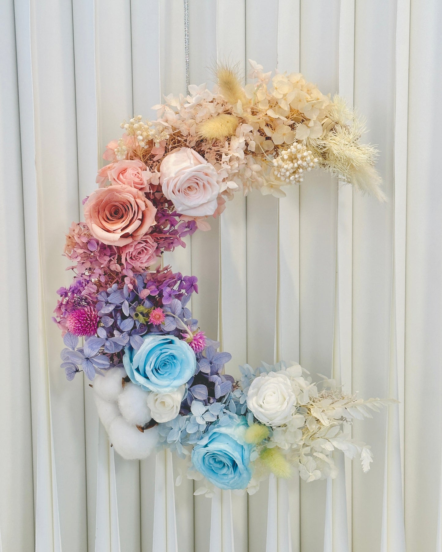 Moon-shaped Lunar Halo wreath with preserved flowers in whimsical pink, white, lilac, and blue tones