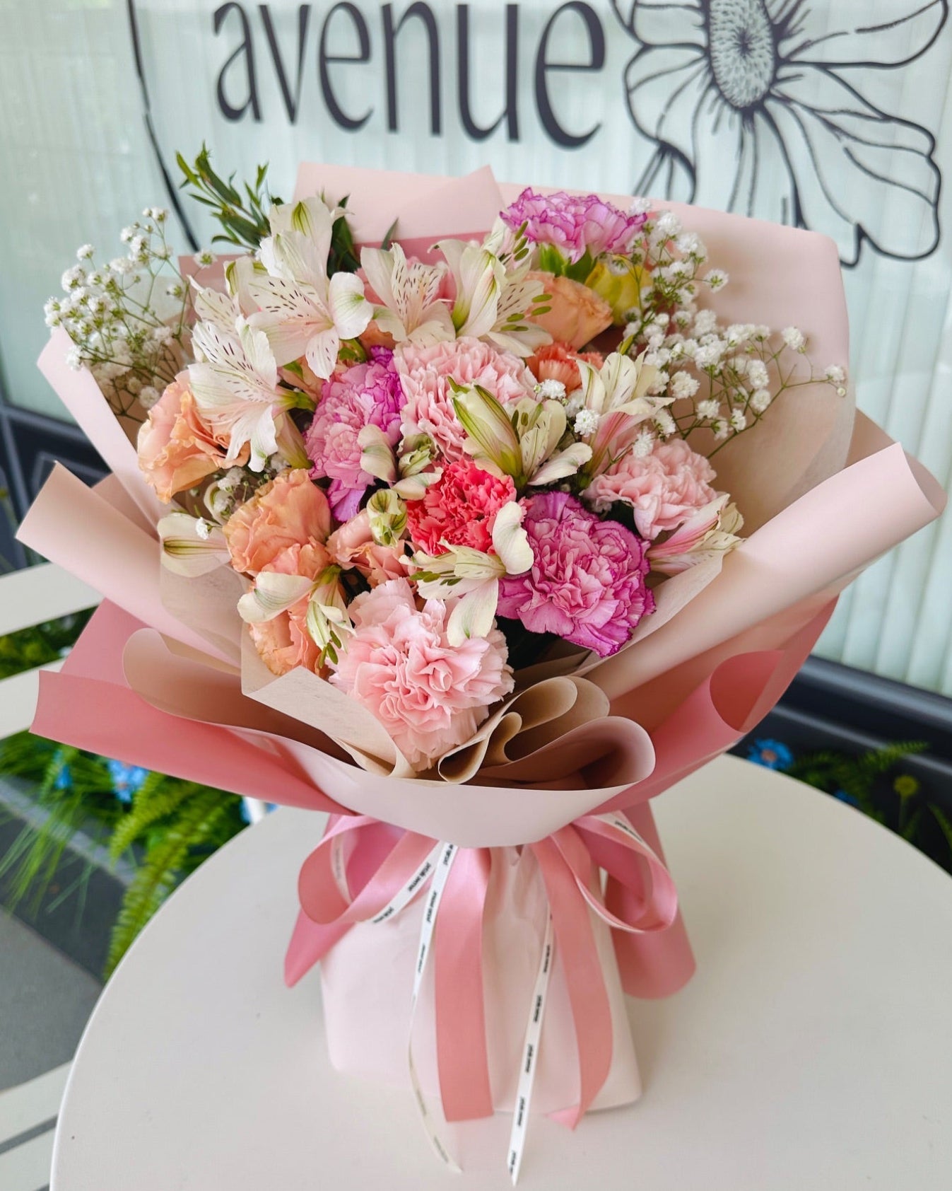 Soft and Light carnation bouquet with chic filler flowers in pastel pinks and whites, hand-wrapped with elegant paper.
