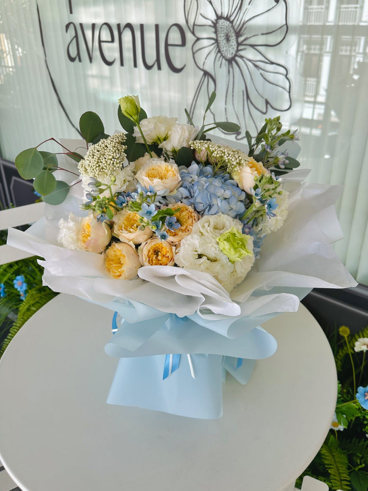 Let the florist decide arrangement with soft blue and white flowers, complemented by delicate filler blooms in a medium-sized hand-tied bouquet.
