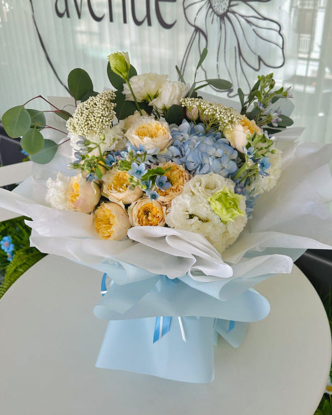 Let the florist decide arrangement with soft blue and white flowers, complemented by delicate filler blooms in a medium-sized hand-tied bouquet.