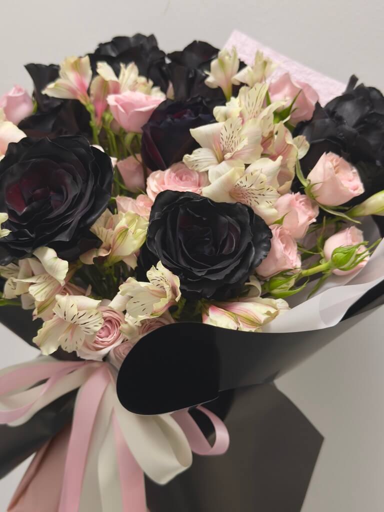 Bouquet of black and pink flowers with a pink ribbon on a light gray background