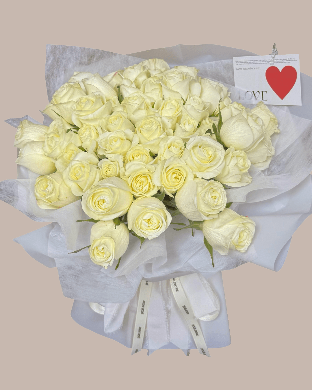 Bouquet of 50 white roses with a 'love' card on a beige background