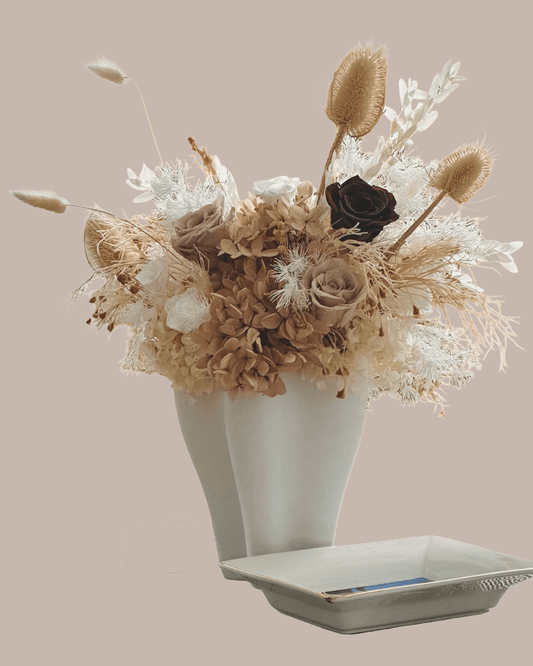 White vase with preserved flowers arranged omakase style.