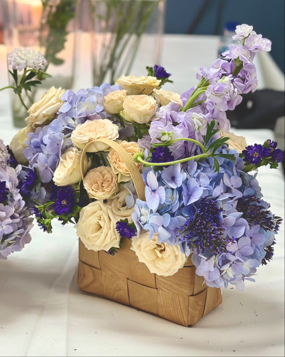 Two flower arrangements in woven baskets on a table with a blurred background