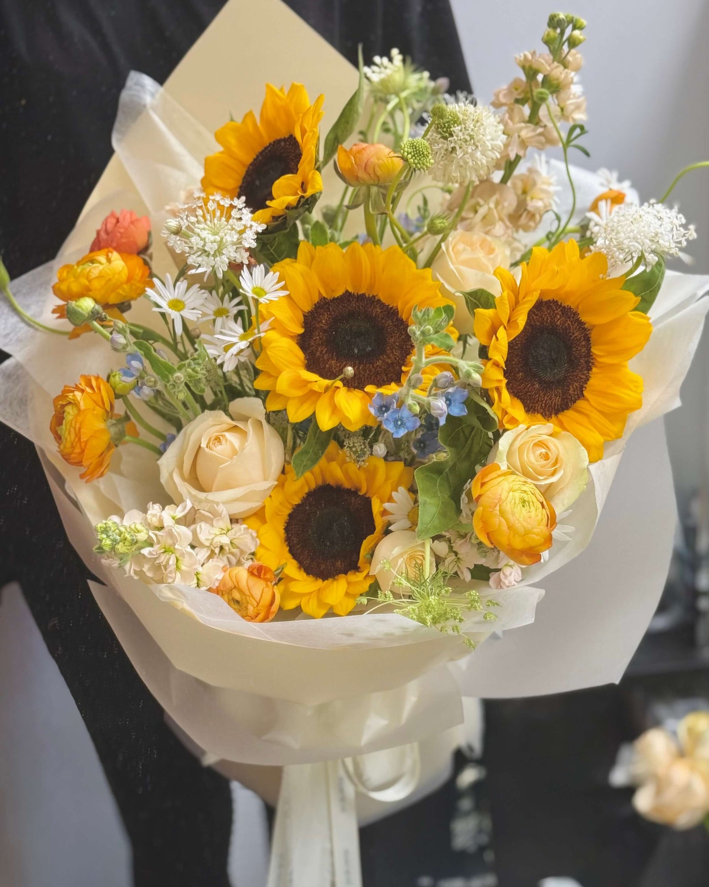 Bright and Vibrant bouquet held in hand, showcasing bold yellow sunflowers and colorful fillers