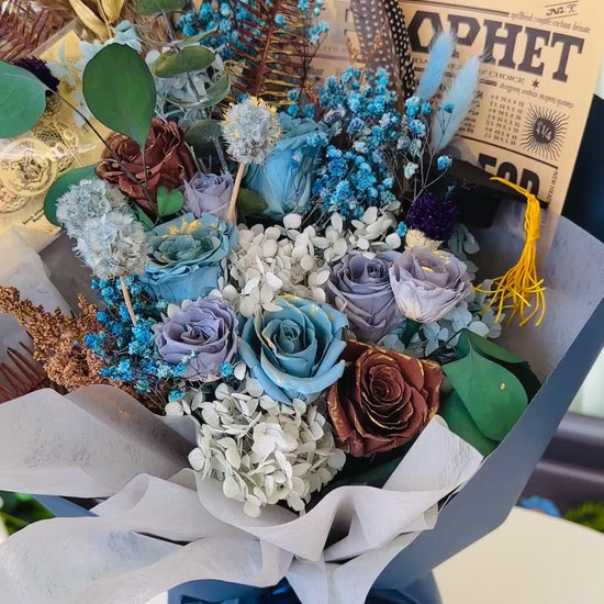 Elegant floral arrangement inspired by Ravenclaw House, with preserved blue and silver flowers and themed accessories.