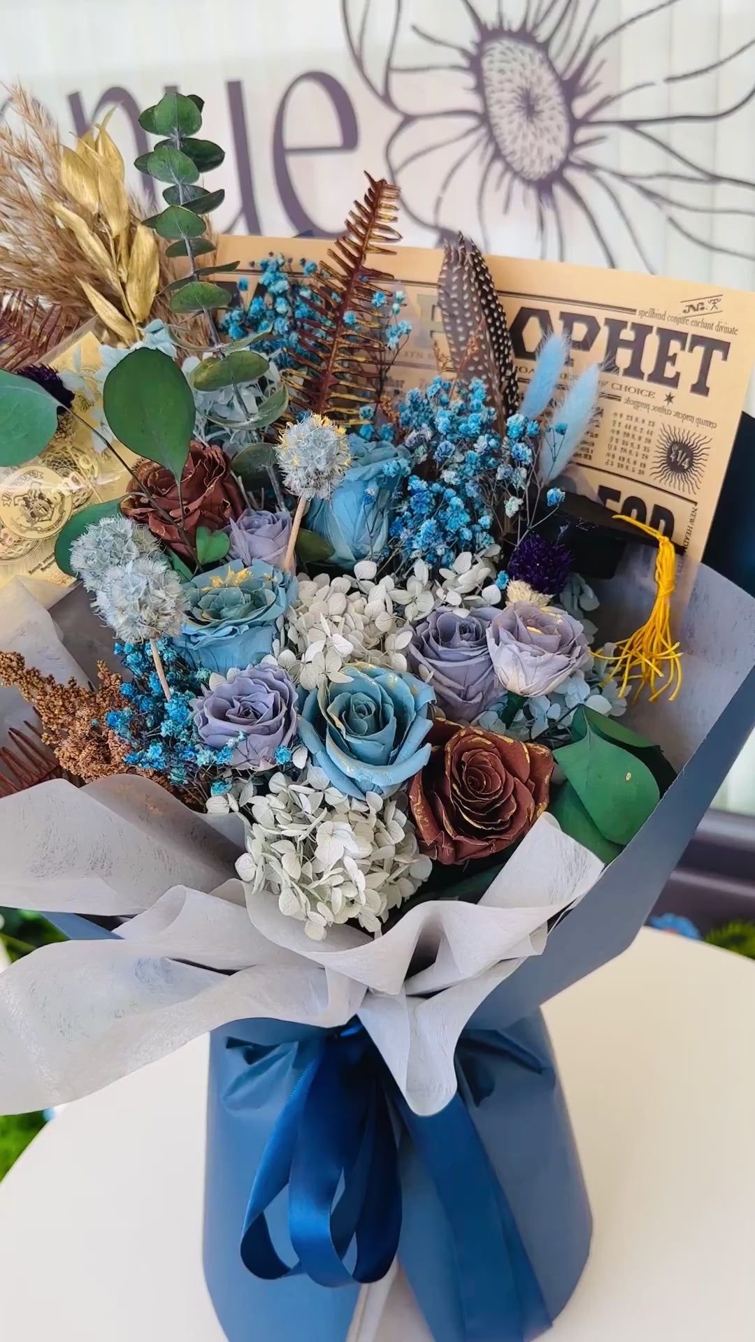 Elegant floral arrangement inspired by Ravenclaw House, with preserved blue and silver flowers and themed accessories.